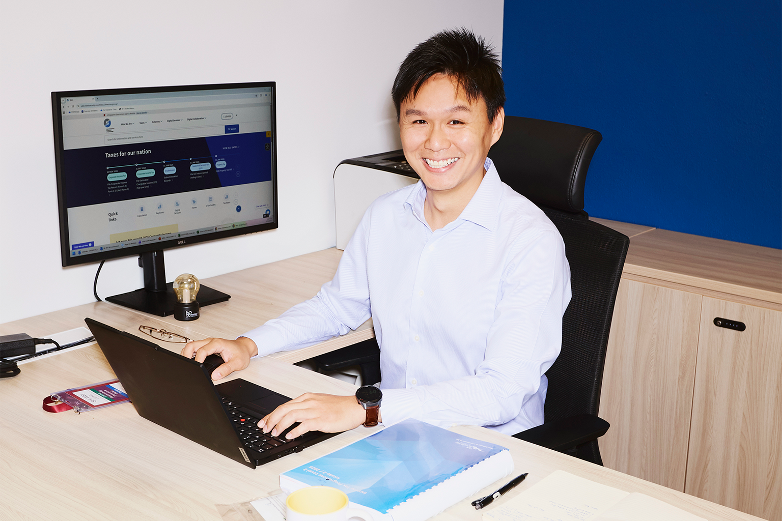 IRAS director Leong Shi Wei sitting at his desk with a laptop and computer.