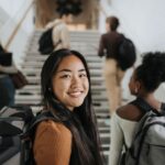 Young Asian female university student standing in front of her classmates who are turned away