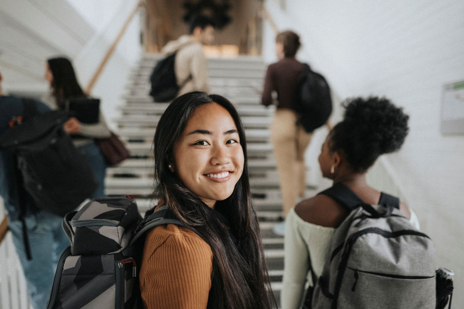 Young Asian female university student standing in front of her classmates who are turned away