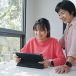 parent guiding her child through a scholarship application on a tablet