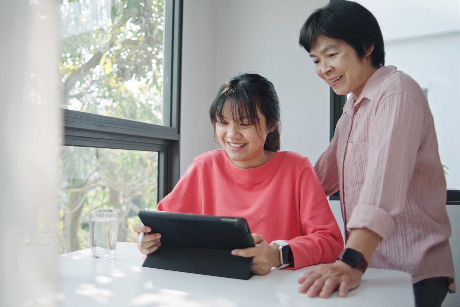 parent guiding her child through a scholarship application on a tablet