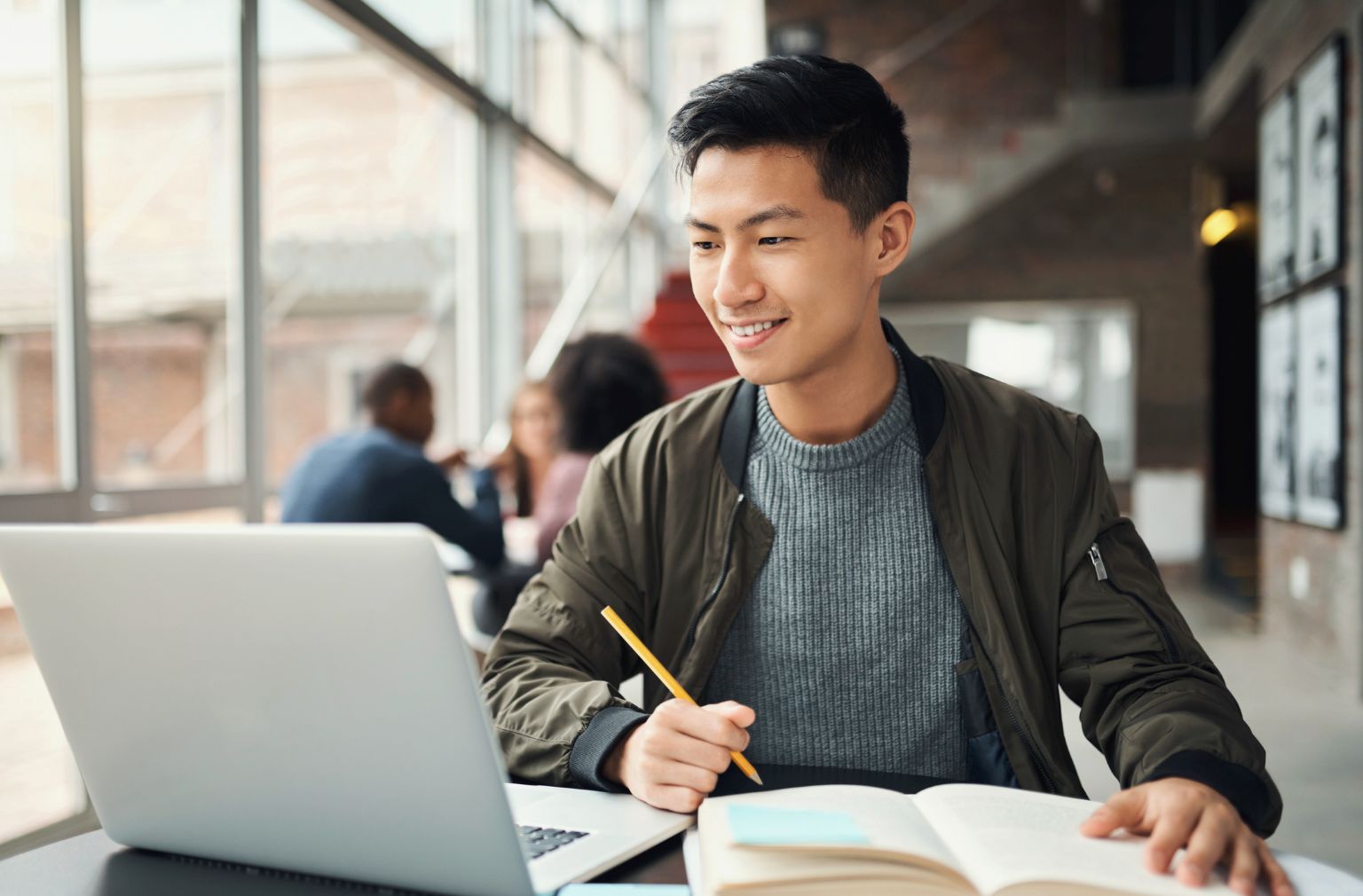 Asian university age boy doing research on his laptop