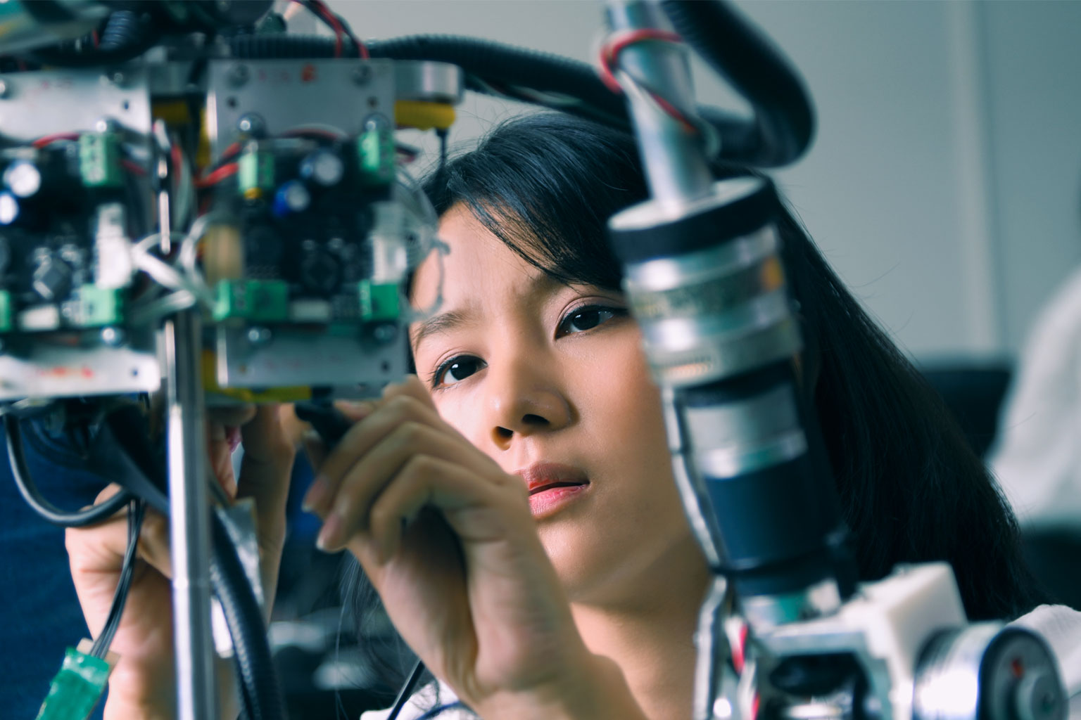 young female student fixing a robot